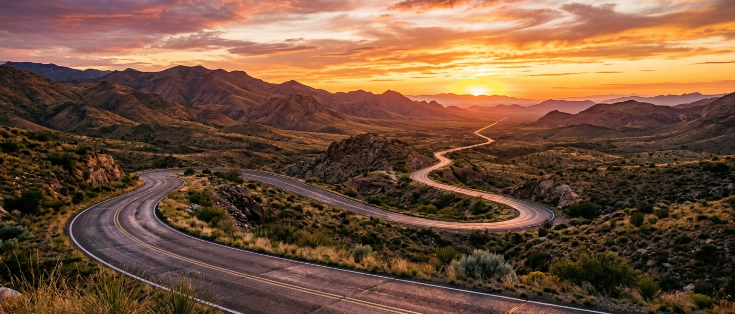 Long, winding road disappearing into a beautiful sunset horizon